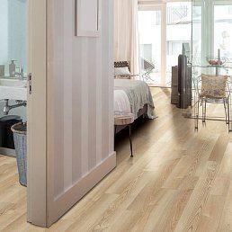 Bedroom with wood flooring and a striped wall, partially visible, leading to a bathroom.