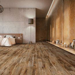Wooden floor in a bedroom with a bed, lamp, and wood-paneled wall.