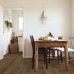 Dining room with wood table and chairs, white walls, and wood flooring.