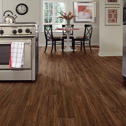 Kitchen with dark wood-look flooring, a stove, table and chairs, and a window.