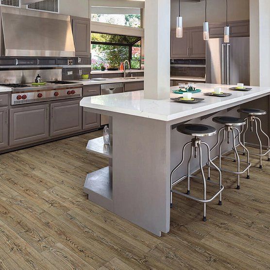 Kitchen with gray cabinets, island with stools, and wood-look flooring.