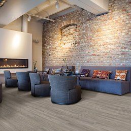 Interior lounge with brick wall, fireplace, and seating with hardwood floors.