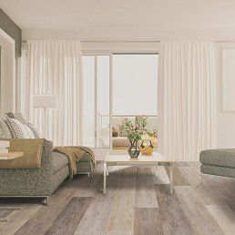 Living room with gray sofa, white curtains, wood floor, and view to a balcony.