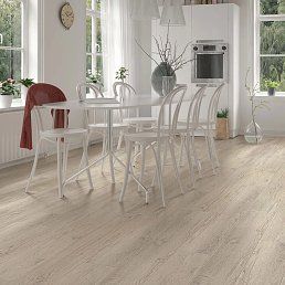 Dining room with a white table, chairs, and light wood flooring.