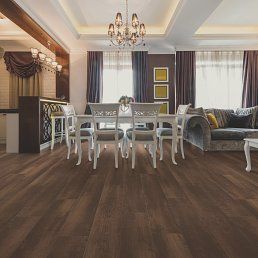 Spacious dining room with wood flooring, chandelier, dining table, and a gray sofa.