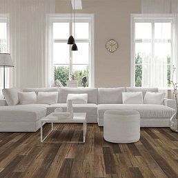 Living room with white sectional sofa, ottoman, and hardwood flooring.