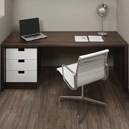 Desk with laptop, white chair, drawer unit, lamp, and papers in a modern office.