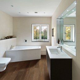 Modern bathroom with a white bathtub, dark wooden vanity, and a large window.