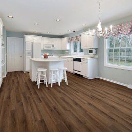 Spacious kitchen with wood floors, white cabinets, and an island with stools. Bright room with large windows.