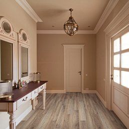 Hallway with wood flooring, antique white console and mirrors, light fixture.
