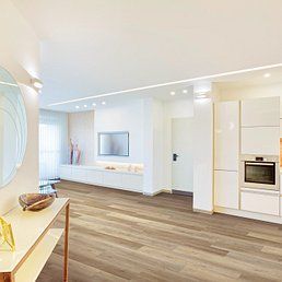 Modern living space with hardwood floors, white walls, and built-in kitchen appliances.