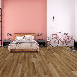 Bedroom with wood-look flooring, pink and white walls, bed, bike, and bedside tables.