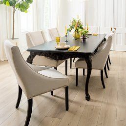 Dining room with a dark table, light chairs, and floral centerpiece.