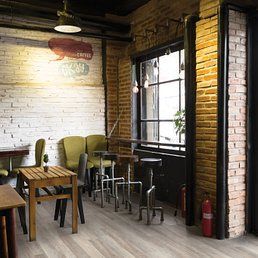 Interior of a cafe with brick walls, a window, and wooden tables and chairs.