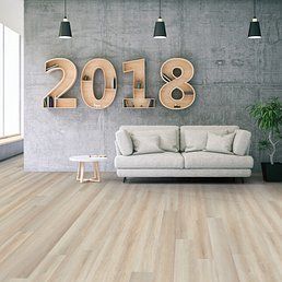 Living room with wooden floor, gray wall, sofa, 2018 art, side table, and three hanging lights.