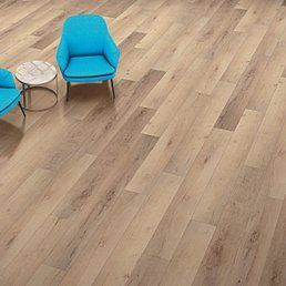 Light wood-look flooring with two blue chairs and a small round table.