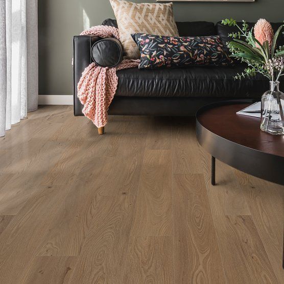 Living room with hardwood floor, black leather sofa with pillows, and a round coffee table.
