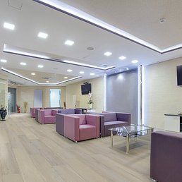 Modern waiting room with purple seating, glass table, and light-colored wood floor.