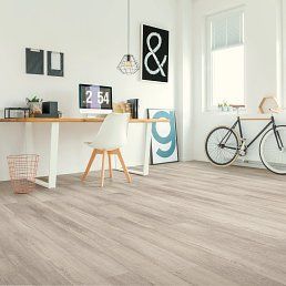 Bright home office with desk, artwork, and bicycle on wooden floor.