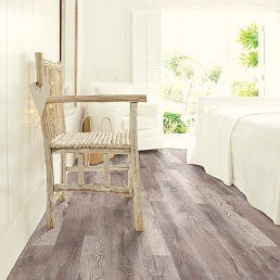 Rustic chair in a room with wood-look flooring. White bedding and a window with greenery are visible.