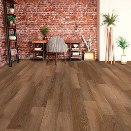 Wooden floor in a room with brick wall, desk, chair, and plants.