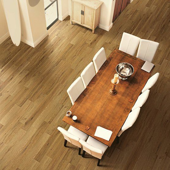 An overhead shot of a dining table with white chairs, set on a wood floor in a bright room.