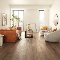 Living room with brown leather sofa, two curved armchairs, and hardwood floors.