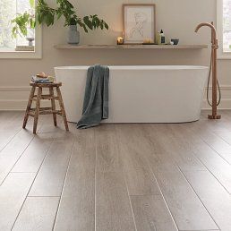 Bathroom with a white tub, wood-look tile floor, and a wooden stool.