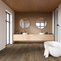 Modern bathroom with wood accents: floating vanity, round mirrors, tub, and slatted ceiling.