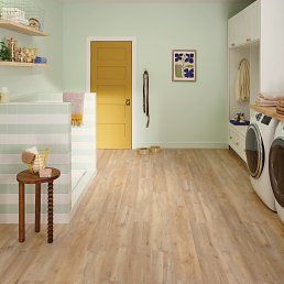Laundry room with light wood floors, washer/dryer, yellow door, and pale green walls.