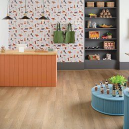 A retail space with light wood floors, a coral counter, and a blue display stand. Dinosaur wallpaper.