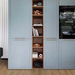 Blue cabinets with built-in shelving and a black appliance in a kitchen.