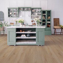 Green kitchen with island and cabinets, marble countertops, and light wood flooring.