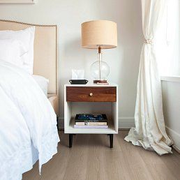 Bedroom with white bedding, nightstand, lamp, and sheer curtains.