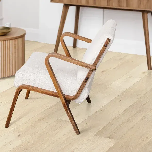 Cream-colored armchair with wooden frame in a room with light wood floors.