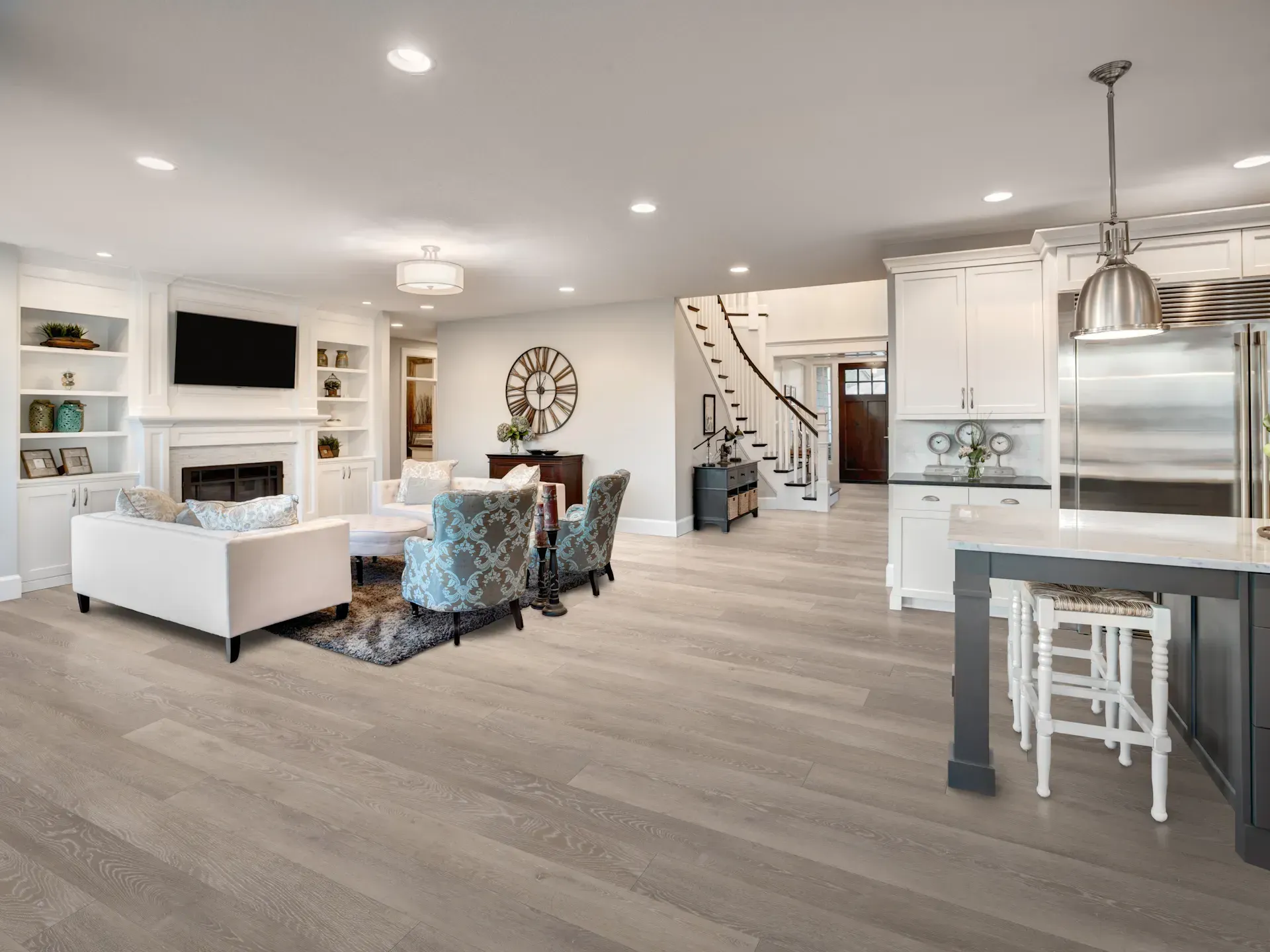 Open-concept living area: Living room with white walls, light wood floor, and kitchen island with stainless steel appliances.