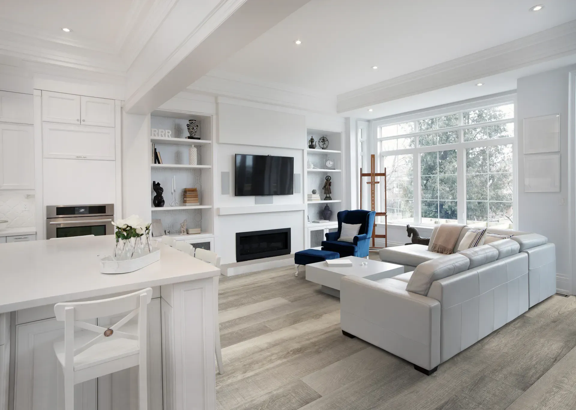 Modern white living space with kitchen island, fireplace, and large window.