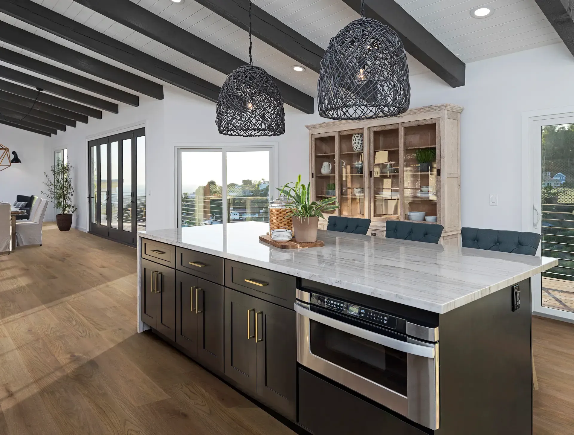 Modern kitchen with dark island, granite countertop, built-in microwave, and decorative lighting.