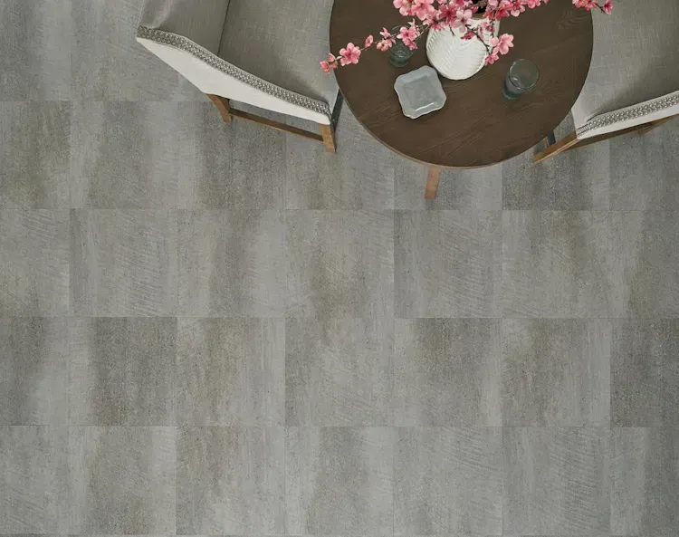 Overhead view of a dining table with two chairs on a gray tiled floor; flowers and decor on the table.