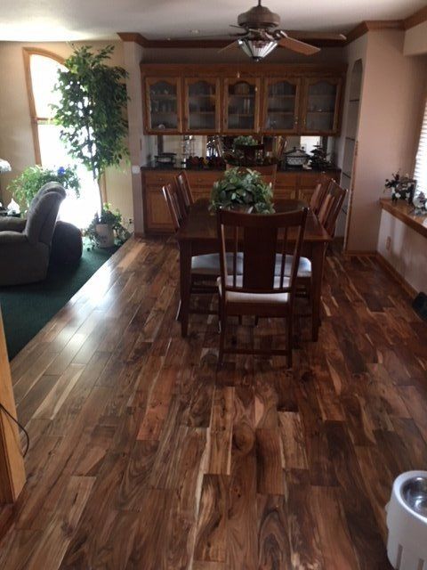 Dining room with wooden floor, table, chairs, and built-in hutch. Large window with recliner visible.