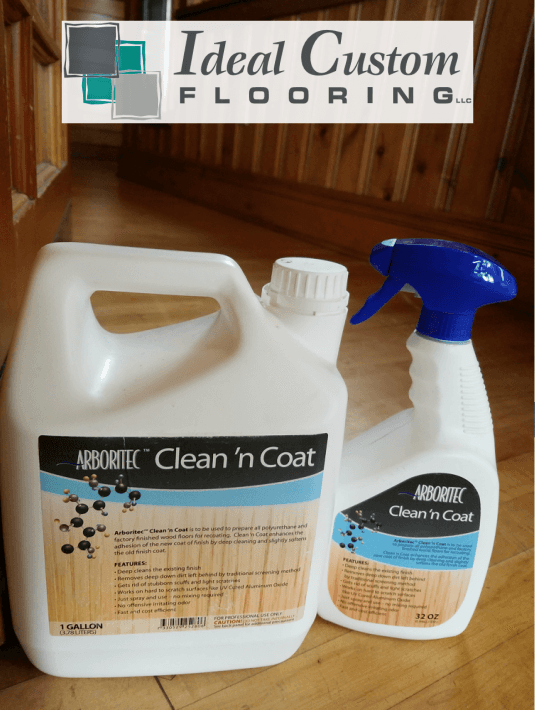 Two white Arboritec Clean 'n Coat bottles with blue labels on a wooden surface, featuring the Ideal Custom Flooring logo.