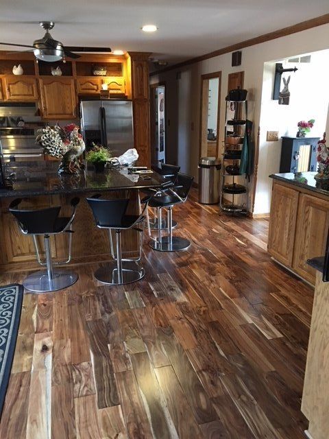 Kitchen with wooden cabinets, island with bar stools, and hardwood flooring.