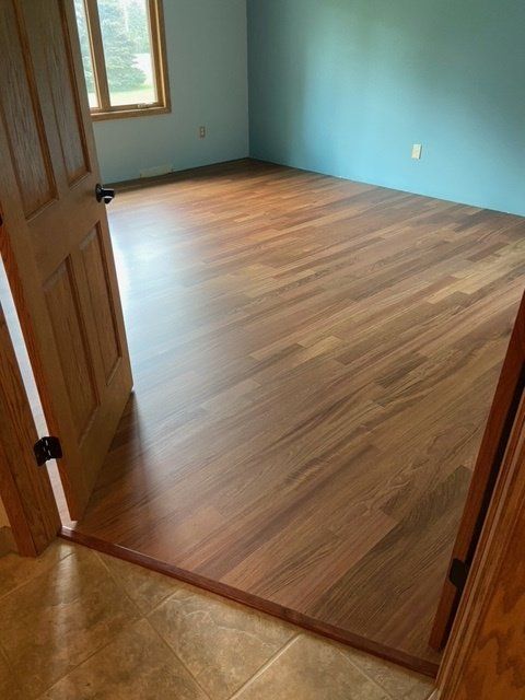 Wooden floor in a room with blue walls, viewed from the doorway.