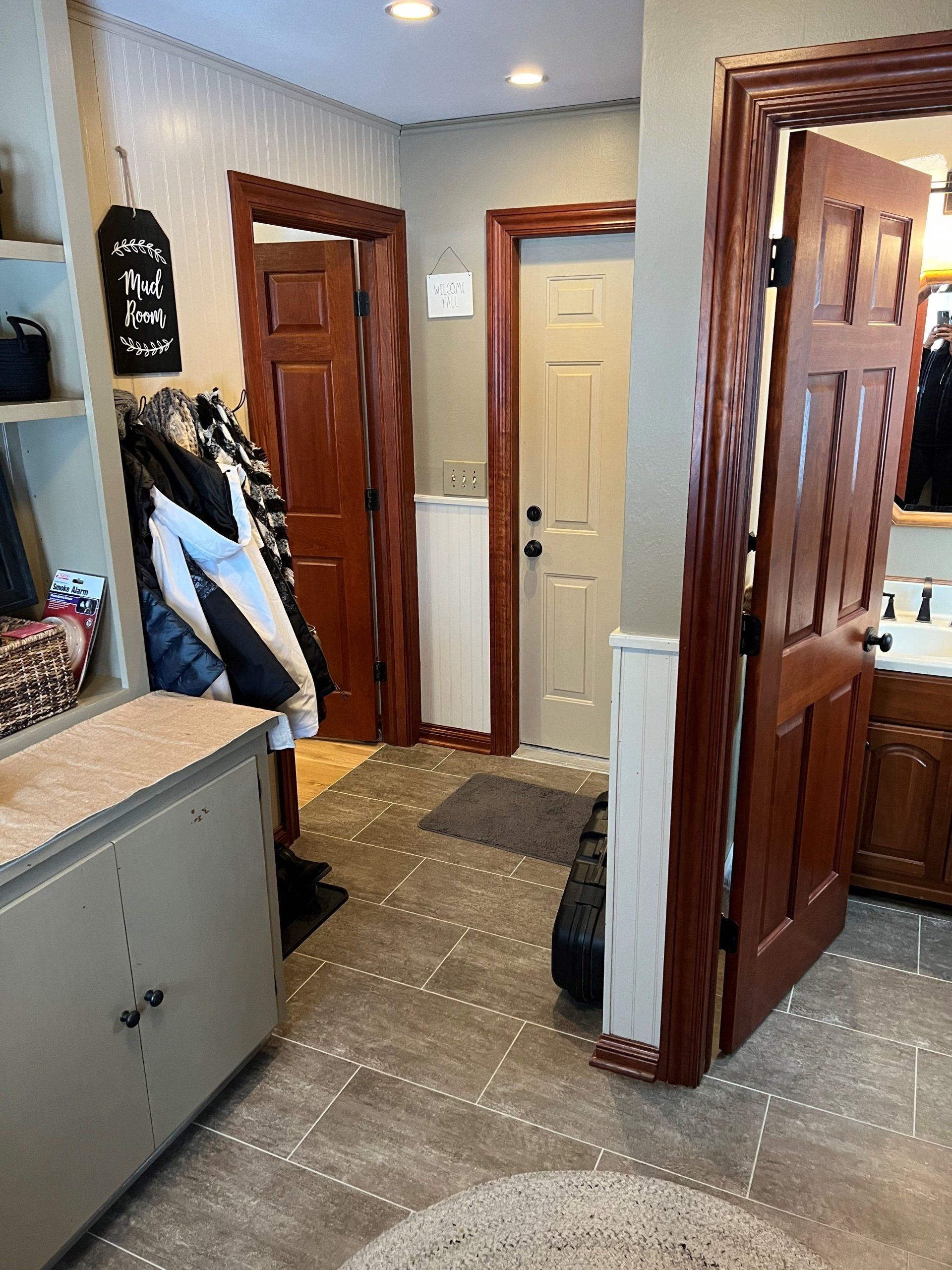 Hallway with doors, storage, coats, and gray tiled floor.