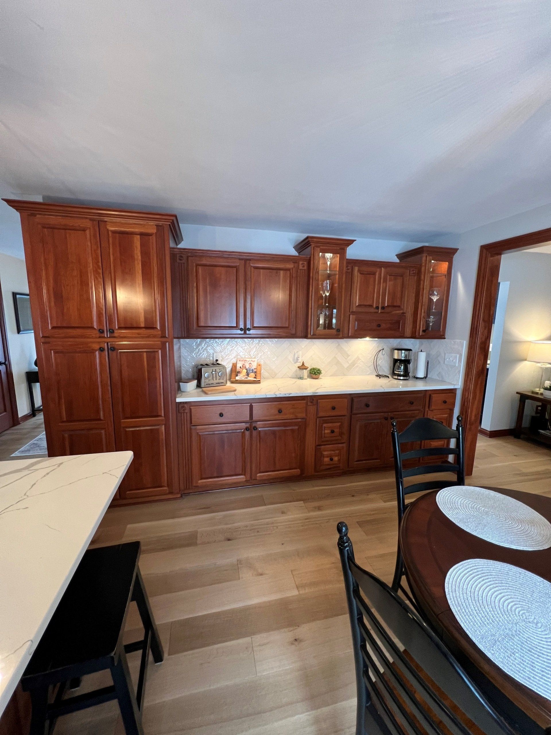 Kitchen with cherry wood cabinets, white countertops, and a round dining table.