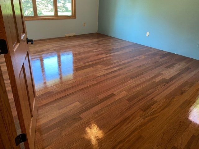 Hardwood floor in room with blue wall and wooden door, sunlight reflection.