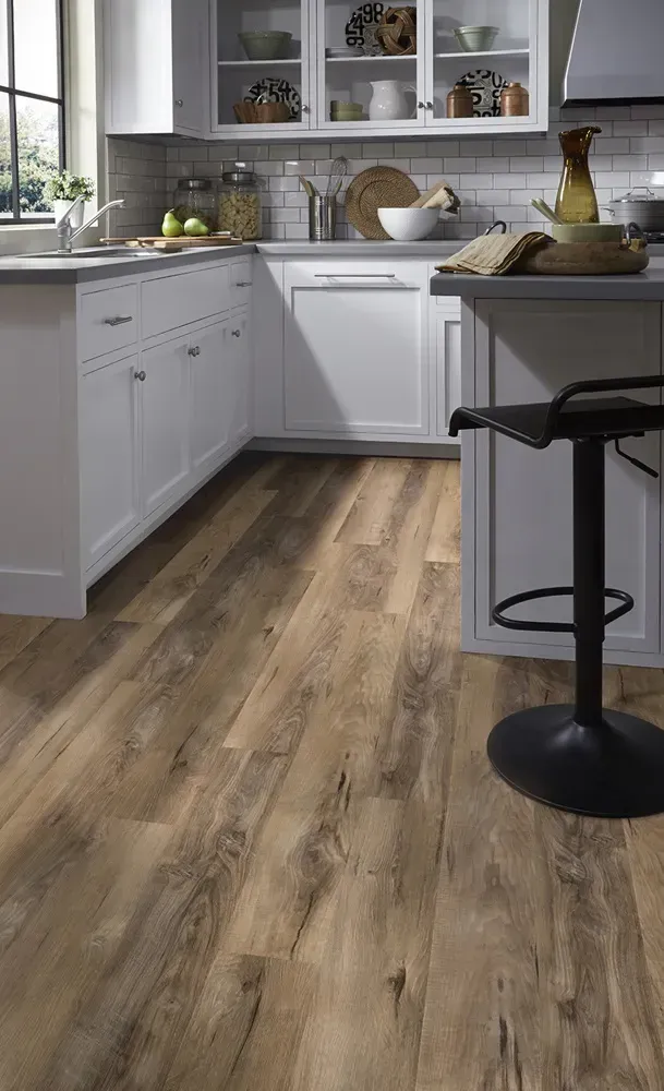 Kitchen with white cabinets, wooden floor, and black bar stool.