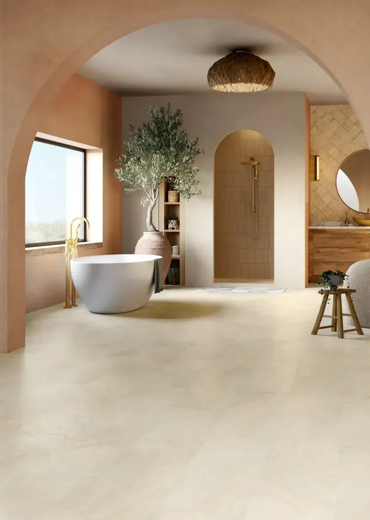 Bathroom with arched doorways, freestanding tub, olive tree, beige and peach tones.
