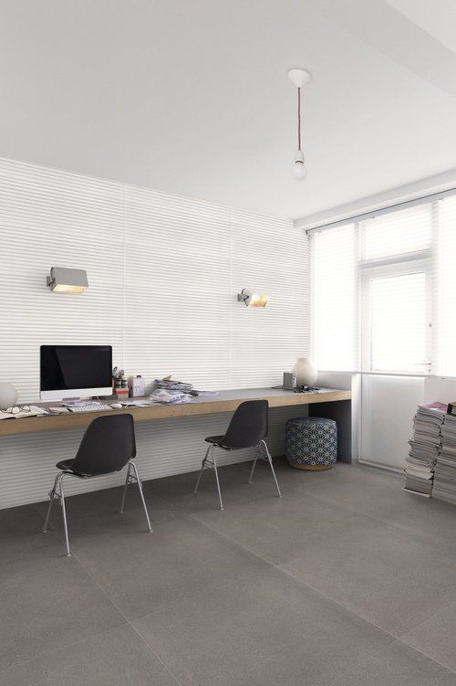 Workspace with long desk, two chairs, a window, and textured white wall. Grey floor and a pendant light.