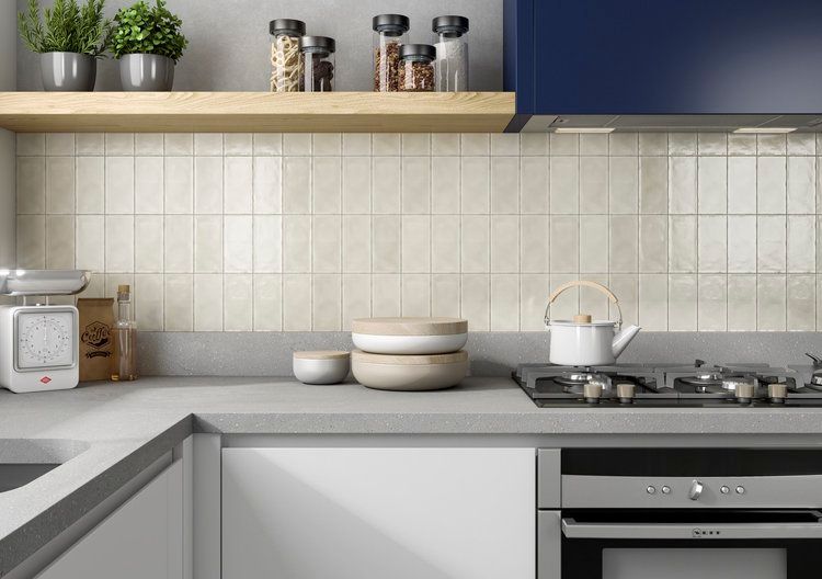 Kitchen with beige tile backsplash, gray countertop, white cabinets, and wooden shelf with plants.